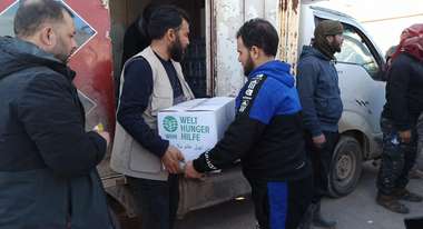 Ein Mann überreicht einem anderen Mann ein Paket mit Hilfsgütern von der Welthungerhilfe