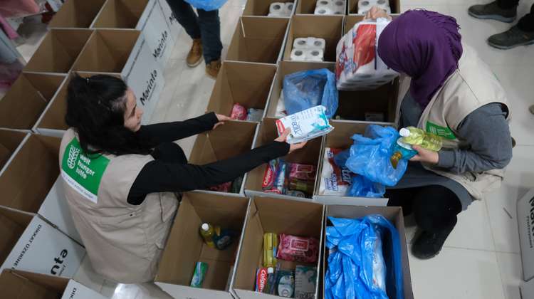 Two women pack boxes with hygiene products.