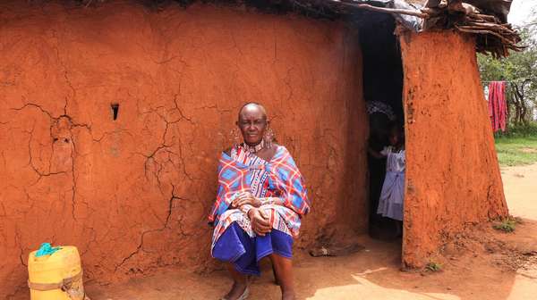 Massai Esther Sululi Makooi vor einer Hütte.