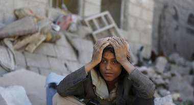 A young man sits next to a heap of rubble.