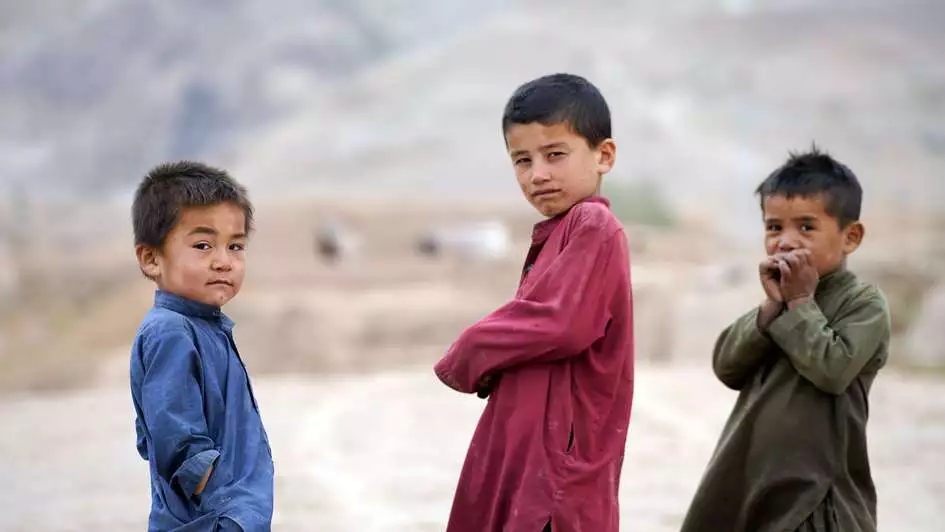 Kinder in Afghanistan Drei Kinder in Afghanistan schauen in die Kamera. Im Hintergrund ist karge Landschaft zu sehen.