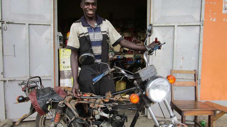Ein Mechaniker im SkillUp!-Programm in Uganda repariert ein Motorrad.