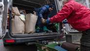 Zwei Personen in der ukrainischen Stadt Ternopil laden Hilfsgüter wie Kleidung und Decken aus einem Transporter.