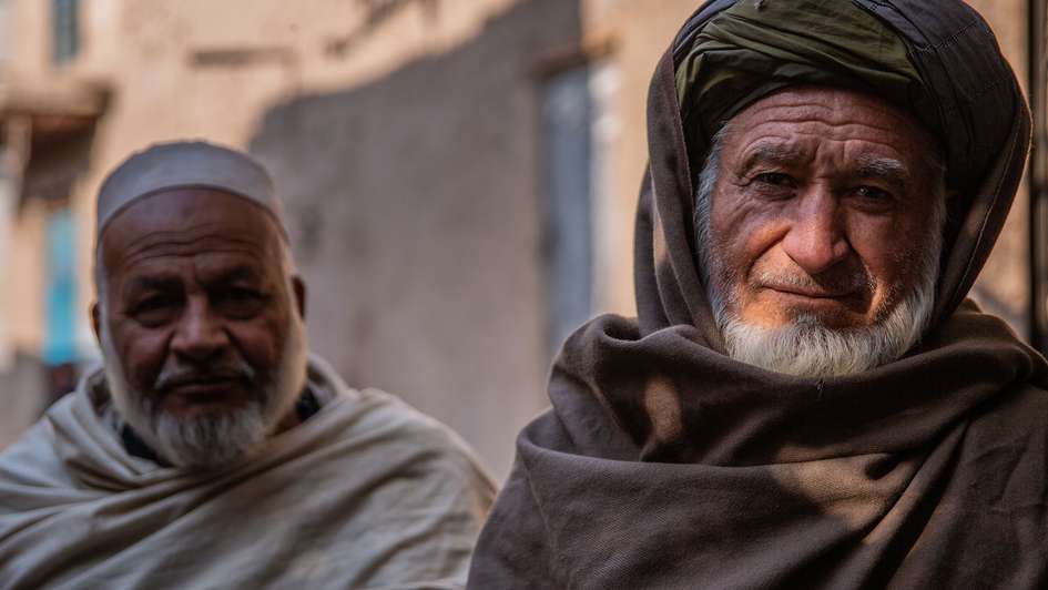 Zwei ältere Männer schauen lächelnd in die Kamera.