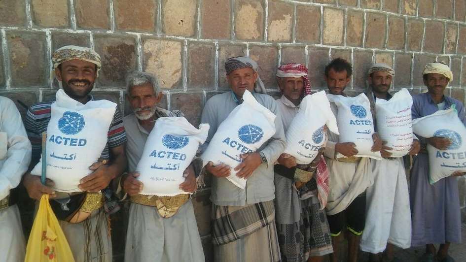Men holding sacks full of seeds labelled 'ACTED'