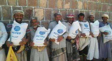 Men holding sacks full of seeds labelled 'ACTED'