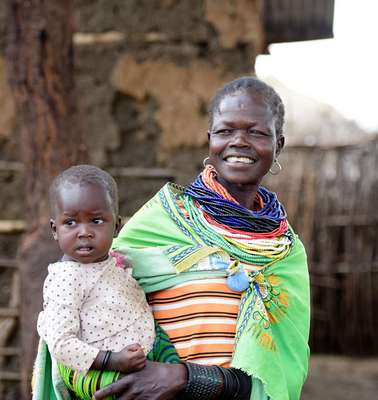 Eine lachende Frau mit einem Baby auf dem Arm.