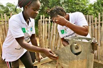 Two young women examine a water pump.