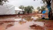 Mud and large puddles between tents in a refugee camp