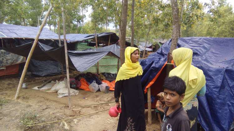 Zwei Frauen und ein Junge vor Zelten in einem Flüchtlingscamp