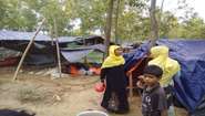 Zwei Frauen und ein Junge vor Zelten in einem Flüchtlingscamp